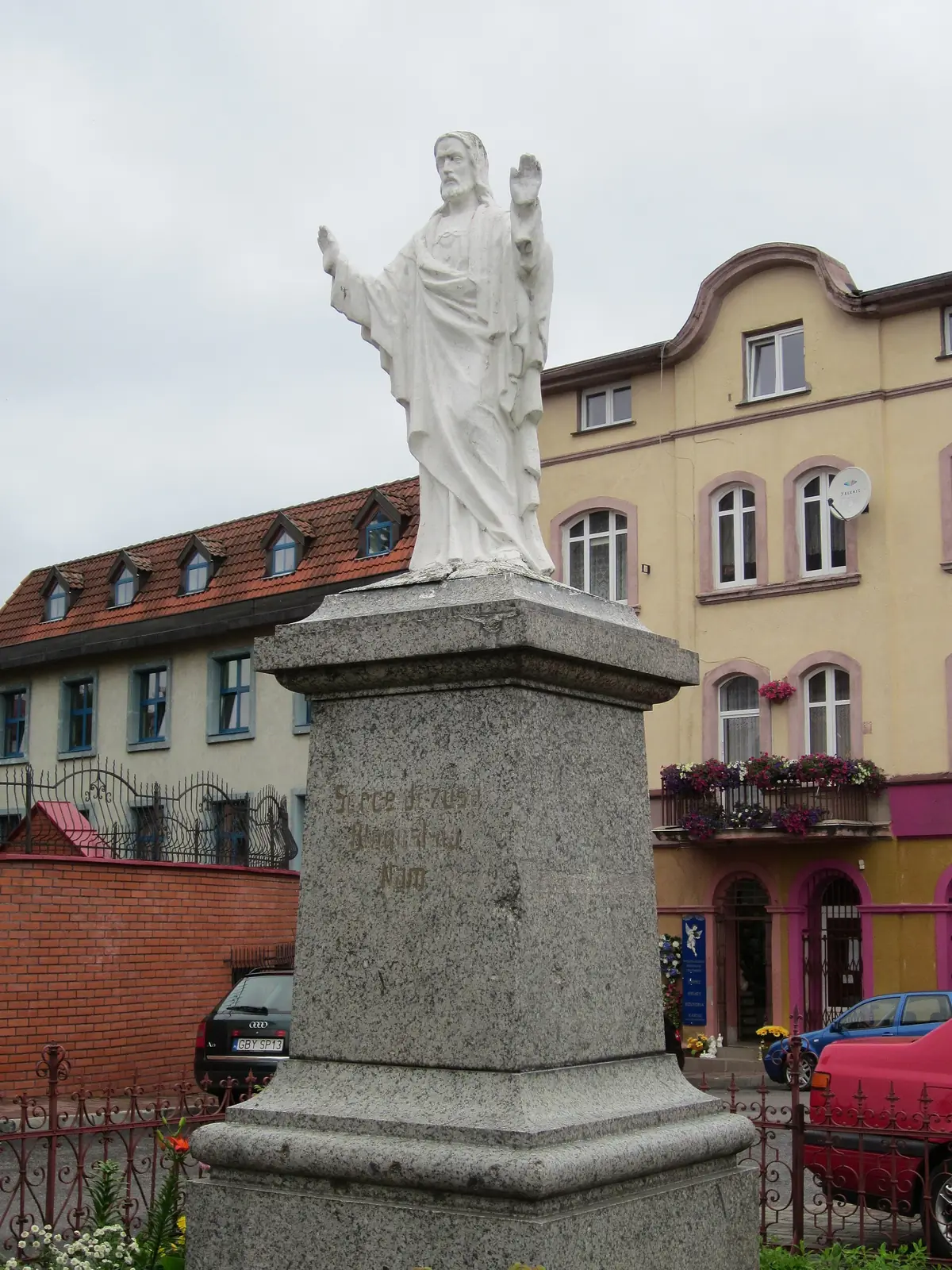 Kamienna figura Chrystusa Króla na wysokim cokole za kościołem w Miastku